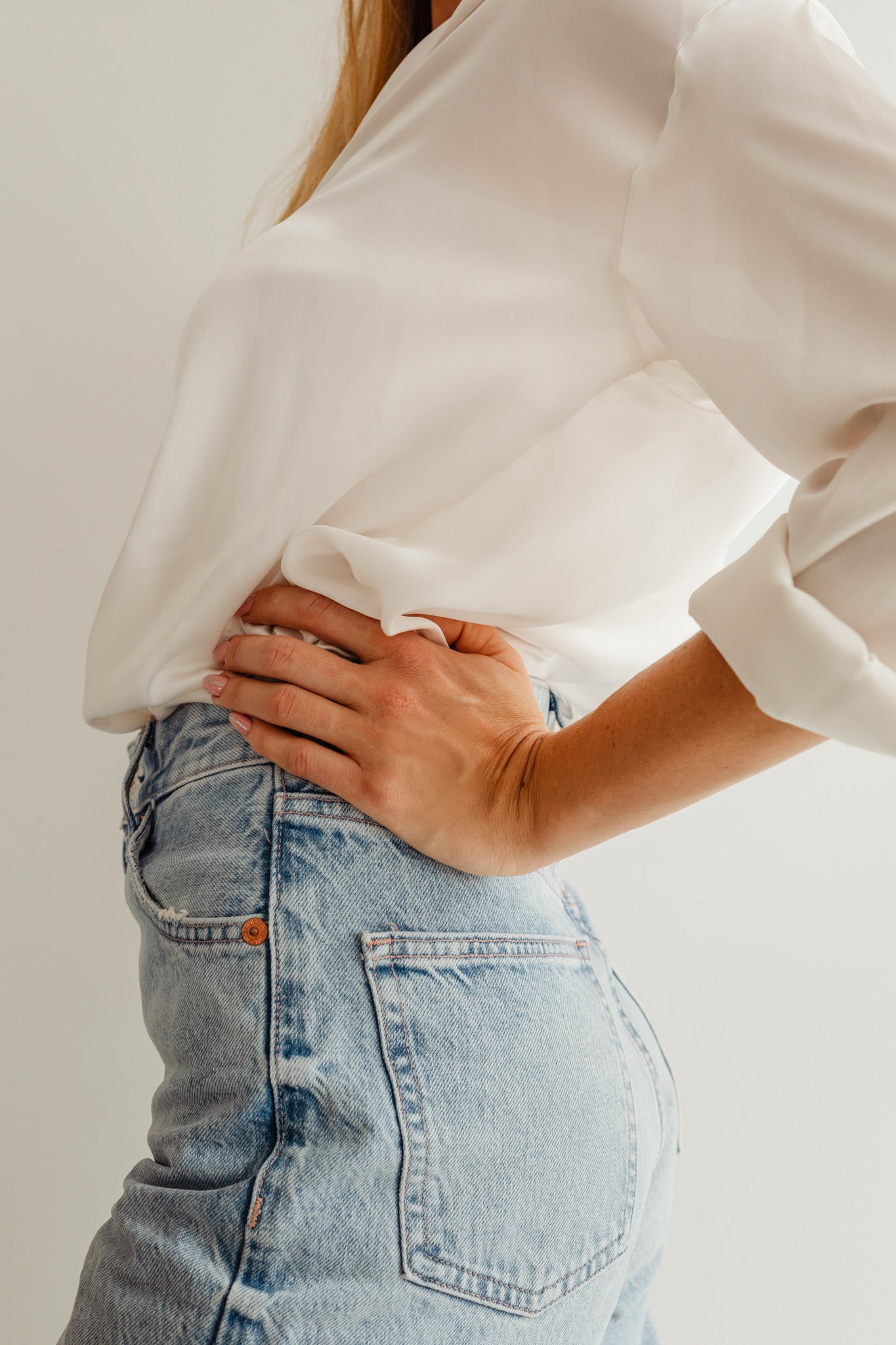 Woman wearing jeans and a white blouse.